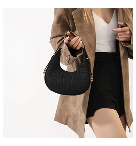 Détail du sac croissant noir avec texture crocodile et boucle de réglage dorée sur la bandoulière