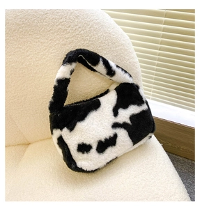Gros plan d'un sac à main en peluche à motif vache sur un canapé beige texturé
