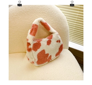 Détail d'un sac à main en peluche à motif vache sur un fauteuil en sherpa beige