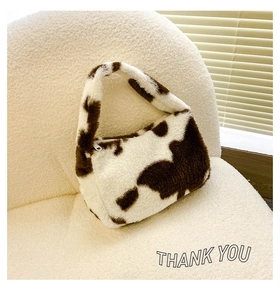 Détail du sac bandoulière en peluche à motif vache avec texture douce et zip argenté