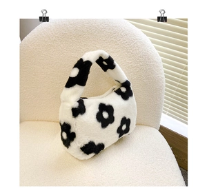 Détail d'un sac à main en peluche à motif floral noir sur une chaise en peau d'agneau