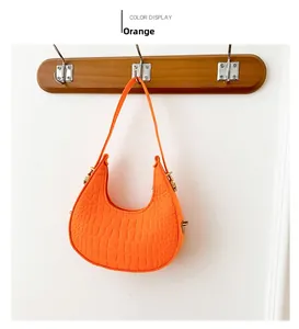 Détail d'un sac demi-lune orange avec gaufrage crocodile et fermeture éclair dorée