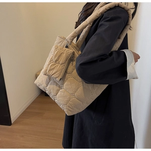 Détail du grand cabas matelassé beige avec mini pochette assortie sur manteau noir