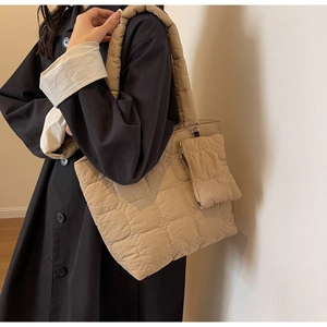 Detail view of khaki quilted tote bag with matching coin purse on a fashion model