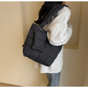 Gros plan d'un sac cabas matelassé noir avec une mini pochette sur un mannequin