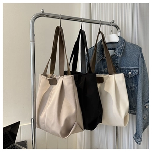 Bolsos tote minimalistas de lona en caqui, negro y crema en un estante de exhibición