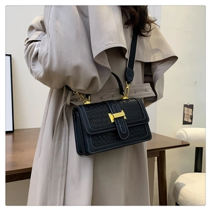 Détail d'un sac à main noir tressé avec fermoir doré et bandoulière large amovible