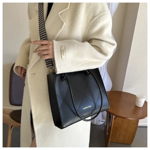 Dettaglio borsa shopper trapuntata nera con tracolla pied-de-poule e scritte oro