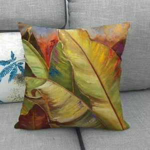 Tropical watercolor banana leaf linen pillowcase on a sofa with warm yellow and green tones