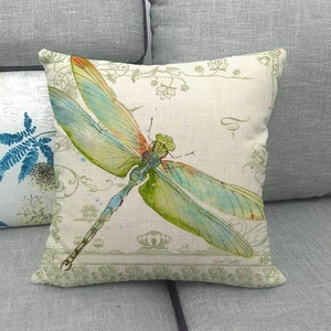 Detail eines Vintage-Libellen-Leinenkissenbezugs mit Blumenbordüren auf grauem Sofa