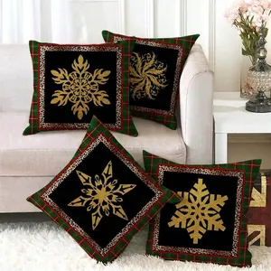Set of four plaid Christmas pillow covers with gold snowflakes on a white sofa