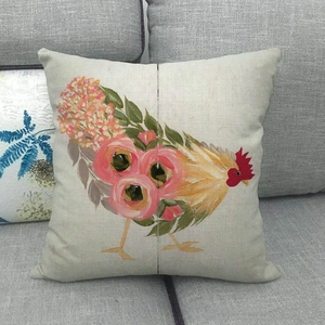 Linen pillowcase with floral rooster pattern on a gray sofa in country style home decor