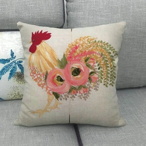 Linen farmhouse pillowcase featuring rooster and rose print on a gray fabric sofa