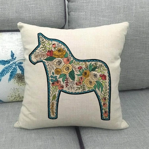 Detail of linen pillowcase with floral Dala Horse print on a soft grey fabric sofa