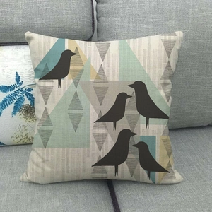 Détail d'un coussin en lin avec motifs nordiques et imprimés d'oiseaux sur un canapé