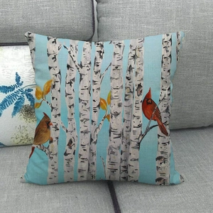 Close-up of red birds and birch trees printed on a linen decorative pillowcase
