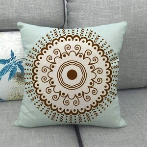 Close-up of light blue linen pillowcase featuring brown mandala pattern on a sofa
