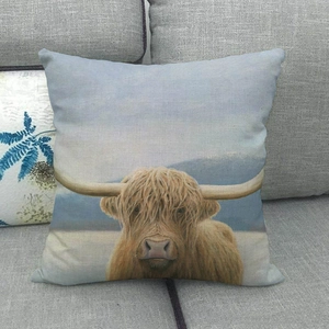 Close-up of a Highland cow printed on a textured linen pillowcase against a sofa background