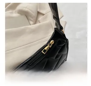 Detailed close-up of smooth gold zipper and quilted black fabric on minimalist shoulder bag