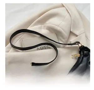 Close-up of black quilted faux leather underarm bag with gold zipper and strap detail