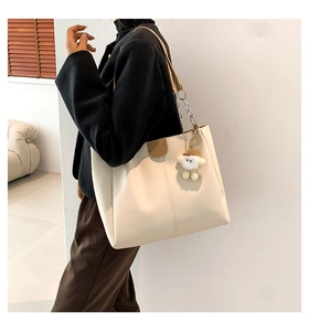 Detail of off-white tote bag with fashion embossing and plush sheep pendant