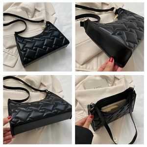 Detail view of black quilted faux leather shoulder bag with golden zipper and sleek finish