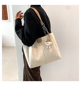 Detail of off-white tote bag with fashion leather patch and chain strap worn by a model