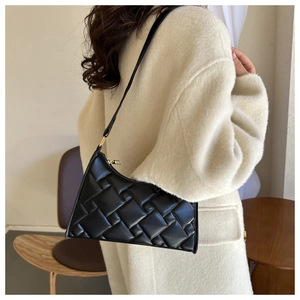 Detail of black woven texture shoulder bag with gold zipper and leather strap