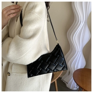 Detail of black woven leather hobo bag worn with a white coat for a stylish fall look