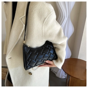 Detail of black woven leather hobo bag with gold zipper shown on woman's shoulder