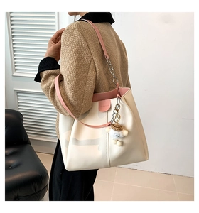 Detail of off-white leather tote bag with pink chain strap and sheep plush charm