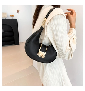 Close-up of black crescent moon bag with golden square buckle and leather texture