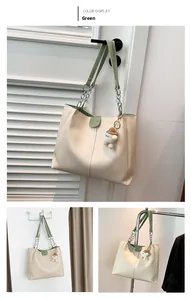 Detail of cream tote bag with green straps, metal chain, and cute teddy bear pendant