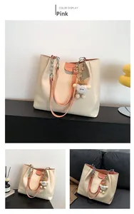 Detail of white PU leather tote bag with pink accents and plush lamb charm accessory