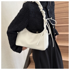 Minimalist ivory leather shoulder bag with ruffled strap and ribbon bow detail on model