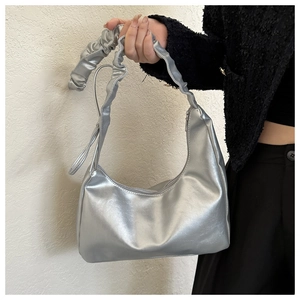 Detail of silver metallic hobo bag featuring a stylish scrunchie handle and minimalist curve