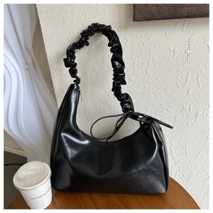Detail of black PU leather hobo bag with pleated cloud handle on wooden surface