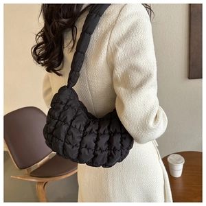 Gros plan d'un sac dumpling matelassé noir porté à l'épaule au fini mat élégant