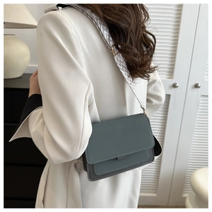 Detail of grey-blue crossbody square bag featuring a decorative jacquard woven strap