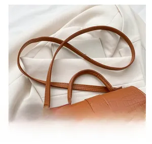 Dettaglio borsa marrone con trama a coccodrillo su sfondo beige professionale