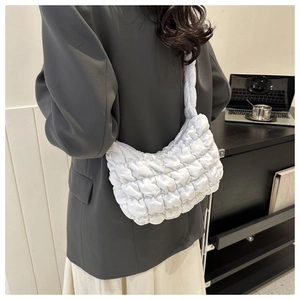 Gros plan d'un sac bandoulière blanc plissé porté par un mannequin dans un bureau sobre