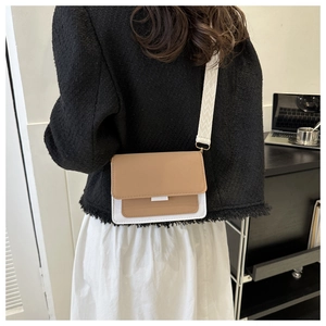 Borsa a tracolla bicolore beige e bianca con ampia tracolla geometrica indossata dal modello