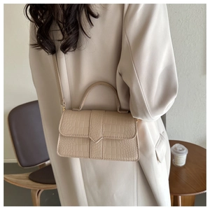 Dettaglio della texture in ecopelle di coccodrillo beige su borsa a tracolla
