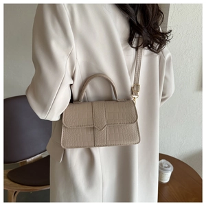 Borsa beige con stampa coccodrillo abbinata a un blazer beige e mobili in legno
