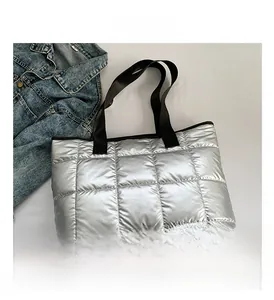 Detailed view of silver quilted tote bag with metallic finish and black shoulder straps