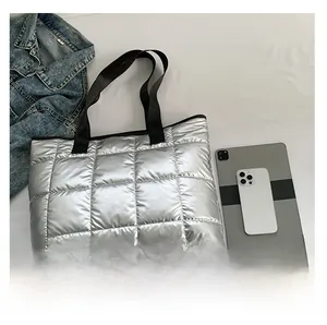 Detailed view of silver quilted tote bag with tablet and phone for size comparison