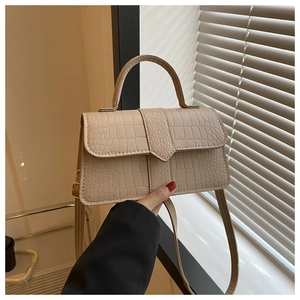 Dettaglio della borsa beige con motivo a coccodrillo, fibbie dorate e texture manico