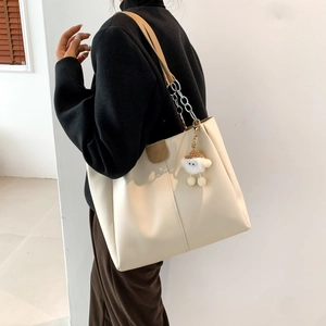 Fashion beige tote bag with chain strap and cute lamb plush charm in minimalist setting