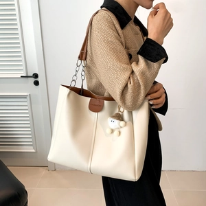Minimalist cream and brown tote bag with chain shoulder strap and plush cloud charm