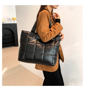 Close-up of quilted glossy black tote bag with large square stitching and fabric strap